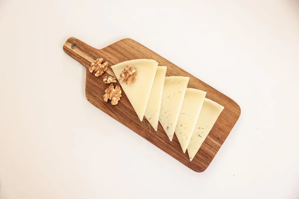 Thin slices of firm cheese and walnuts on a wooden board