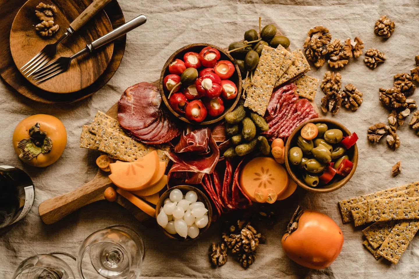 A table of Spanish produce: cured ham and chorizo, olives, stuffed peppers, walnuts and crackers